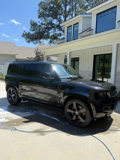 Black Jeep Renegade parked in driveway in front of modern two-story white house with blue-trimmed windows