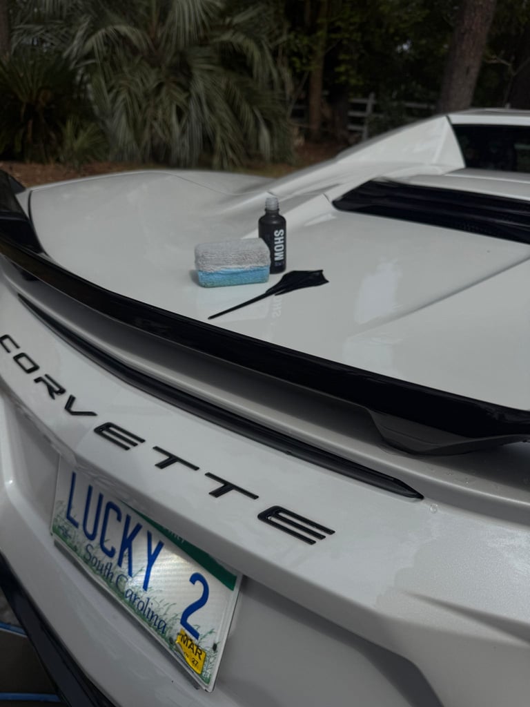White Corvette sports car hood with cleaning supplies and Lucky 2 license plate visible