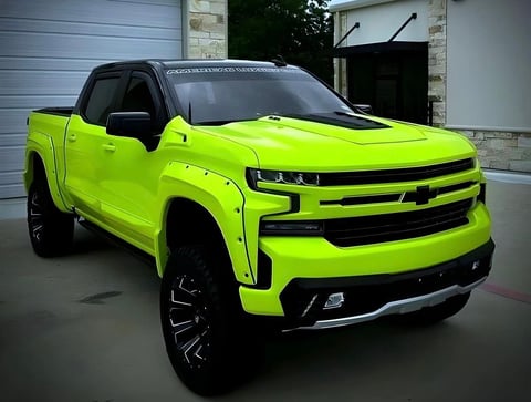 Neon green Chevrolet Silverado pickup truck with black accents parked in a driveway