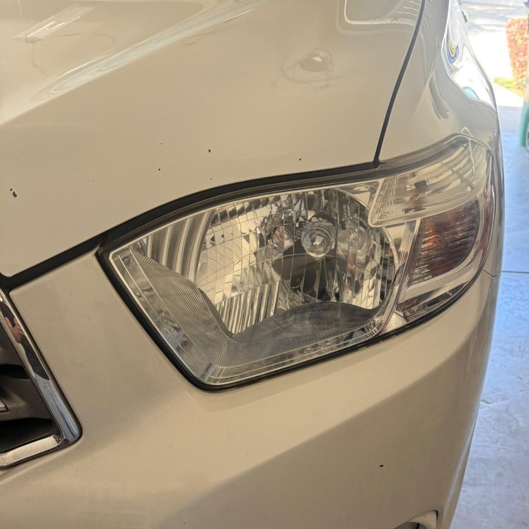 Close-up of a white cars headlight assembly mounted on the front bumper area