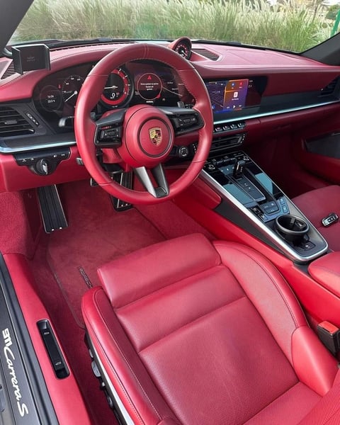 Porsche sports car interior with bright red leather seats, steering wheel, dashboard, and touchscreen display