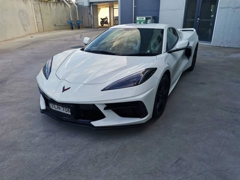 White sports car parked in an industrial lot with buildings in the background